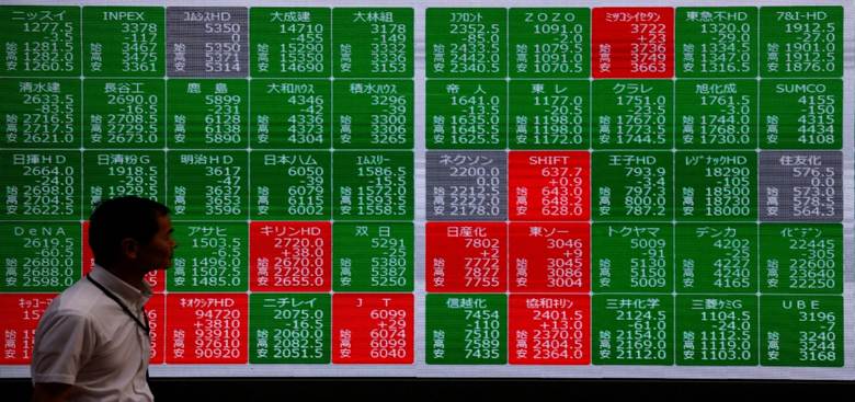 A man walks past a stock quotation board showing the  Nikkei stock prices outside a brokerage in Tokyo